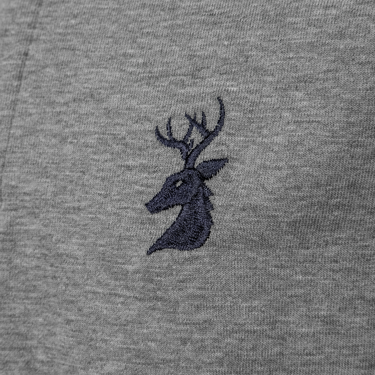 Close-up of the navy embroidered stag head logo on the Spika GO Advance kids' grey rugby jumper
