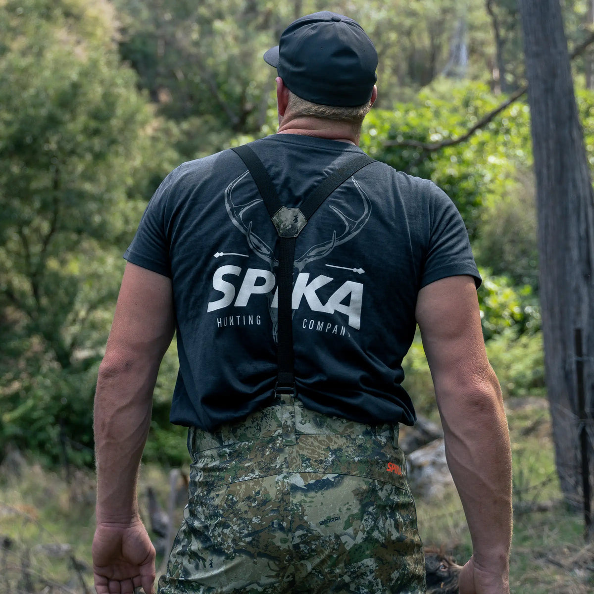Hunter seen from behind in a Spika t-shirt with Edge Biarri Camo pants and braces in the bush