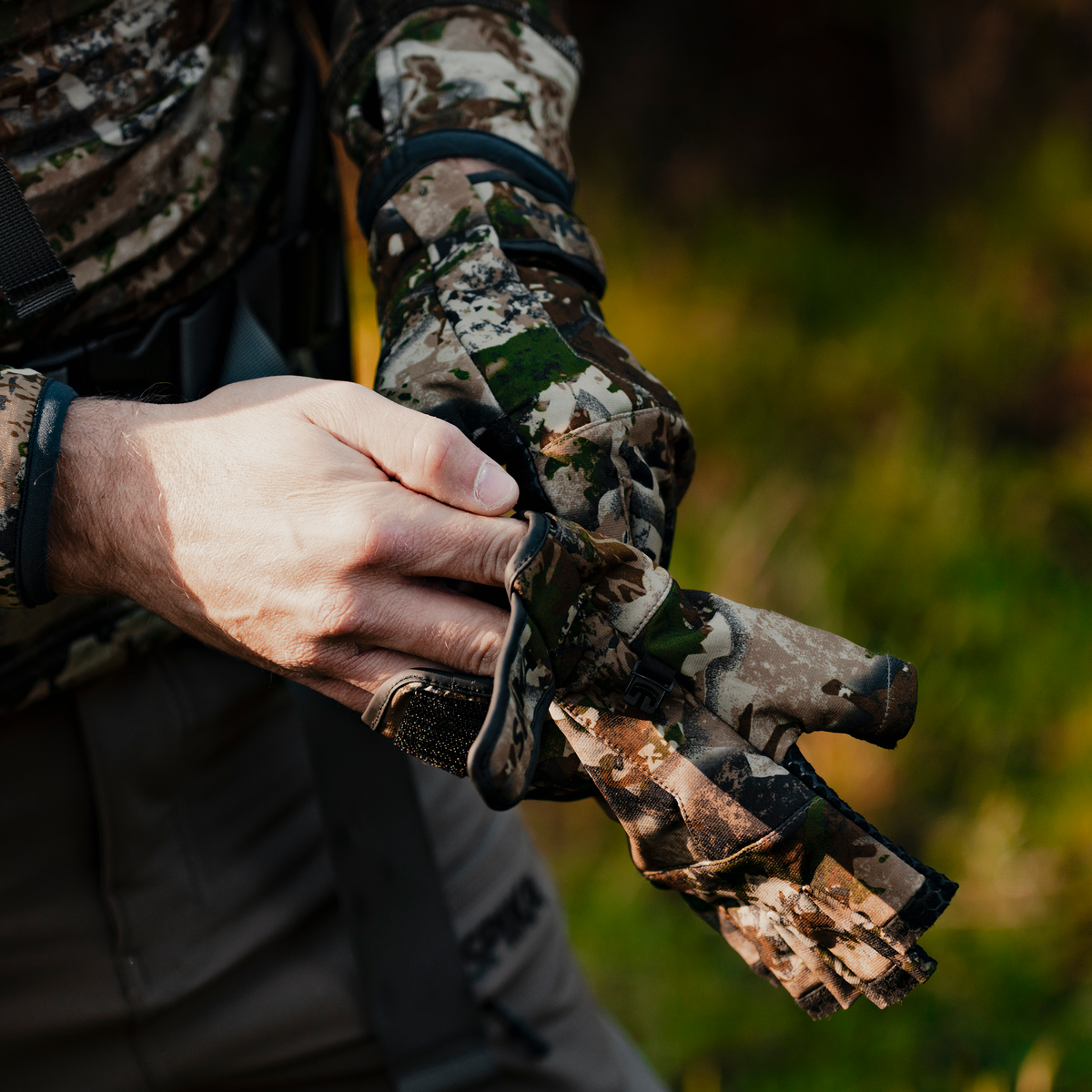 Hunter pulling on Spika Precision fingerless gloves in Biarri Camo in the bush