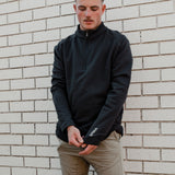 Man in the Spika GO Belay slate quarter-zip jumper adjusting the cuff, showing the SPIKA sleeve logo