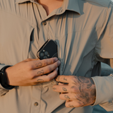 Man sliding a phone into the zip chest pocket of a Spika Skipper men's shirt in Marine