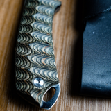 Close-up of the Spika Bushmaster Dogtooth knife handle showing wave texture, screw and lanyard hole