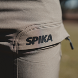 Spika Recon women's pants, outdoor close-up of the rubberised Spika logo on the cargo pocket