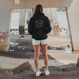 Woman in the Spika GO Contour black hoodie standing under a bridge, rear view of mountain print