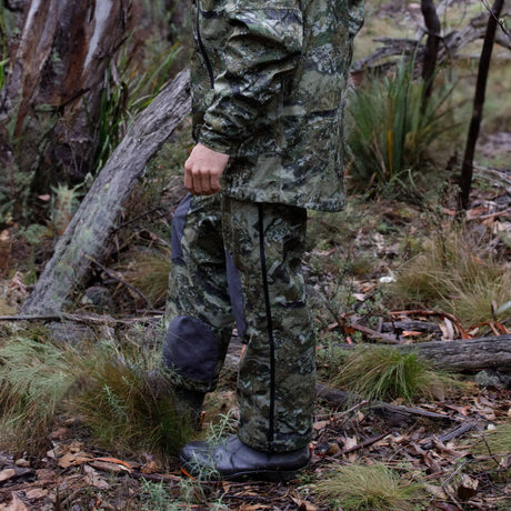 Hunter standing among fallen timber wearing Spika Edge waterproof pants and jacket