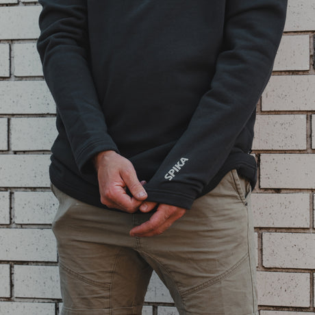 Close-up of the SPIKA logo on the cuff of the Spika GO Belay men's slate jumper worn with chinos