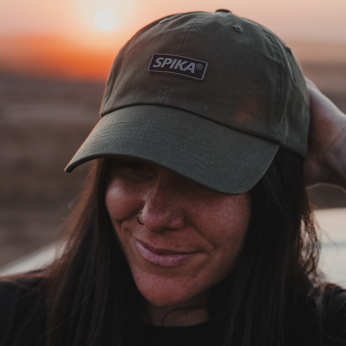 Woman wearing the Spika GO Advance dad cap in Olive outdoors at dusk, hand behind her head
