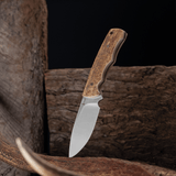 Spika Bushmaster Jeremiah fixed blade knife standing blade down against weathered timber and antler