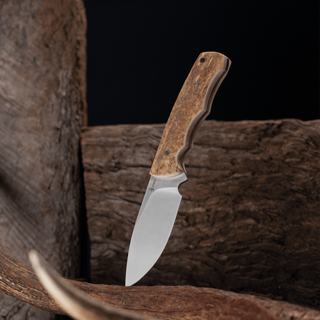 Spika Bushmaster Jeremiah fixed blade knife standing blade down against weathered timber and antler