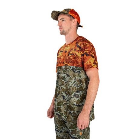 Man modelling the Spika Trail men's T-shirt in Biarri Blaze with a blaze cap, three-quarter view