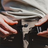 Spika Recon women's pants, hands fastening the webbing belt buckle at the waist