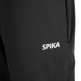 Close-up of the white SPIKA logo on the front thigh of Spika GO Casual women's black jogger pants