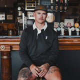 Man wearing the Spika GO Advance men's rugby jumper in slate with white collar, seated at a pub bar