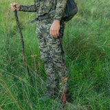 Hunter wearing Spika Recon men's pants in Biarri Camo standing in long grass with a walking stick