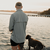 Man in Spika Skipper men's shirt in Marine standing on a jetty with his dog, rear view