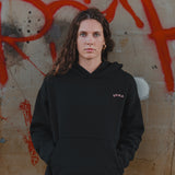 Woman wearing the Spika GO Contour women's black hoodie in front of a graffiti wall, waist-up